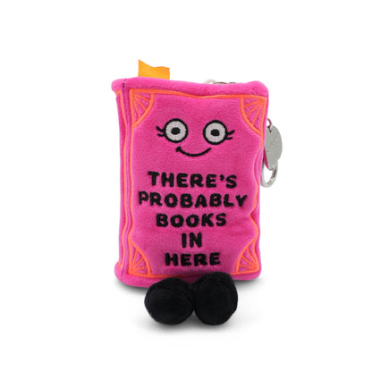 Close-up detail of pink "There's probably books in here" book plush bag charm with smiling embroidered face and decorative orange stitching