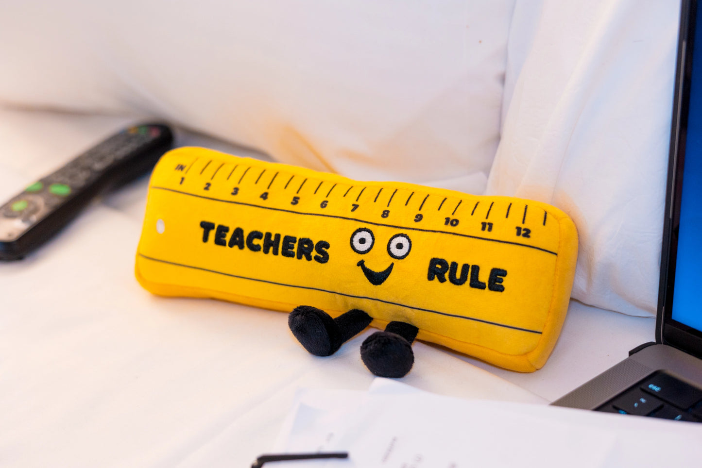 Punchkins Teachers Rule Plush Ruler sitting on white surface next to a laptop — perfect teacher desk décor