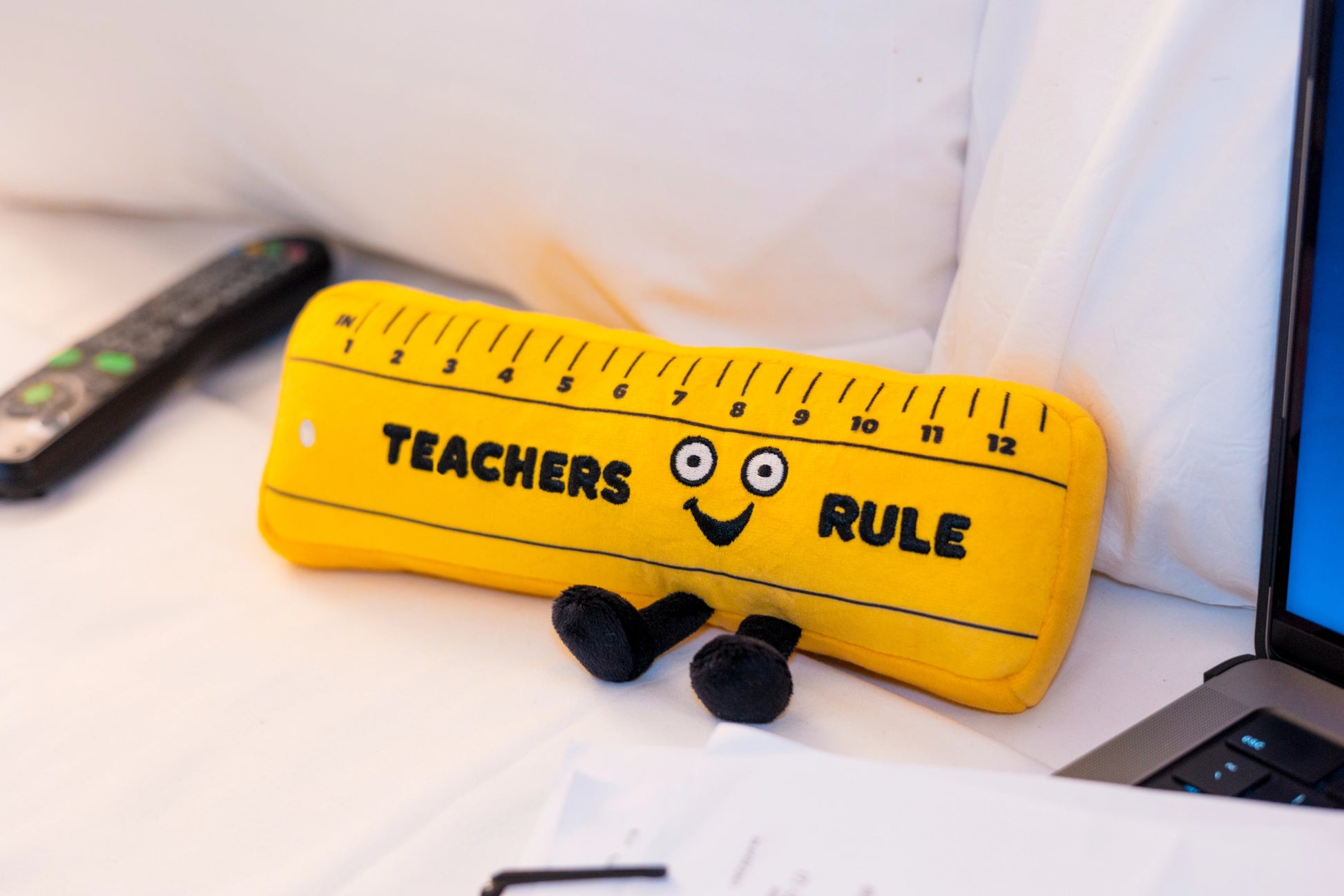 Punchkins Teachers Rule Plush Ruler sitting on white surface next to a laptop — perfect teacher desk décor